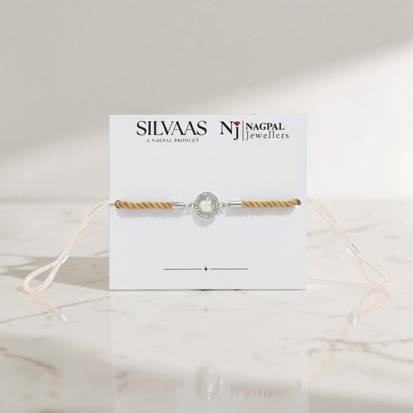 SILVAAS premium silver apple logo Rakhi featuring a stone-encrusted halo on a beige cord, presented on display card.