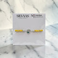 SILVAAS silver Krishna Ji rakhi featuring a circular centerpiece with a peacock feather design on a yellow thread