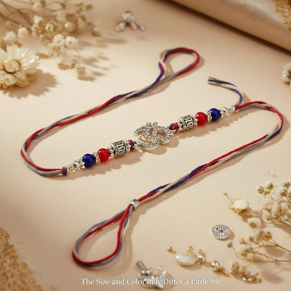 SILVAS Om symbol rakhi bracelet with red and blue beads and silver accents on a beige background