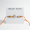SILVAS peacock feather design silver rakhi bracelet with yellow patterned beads and red thread on a display card