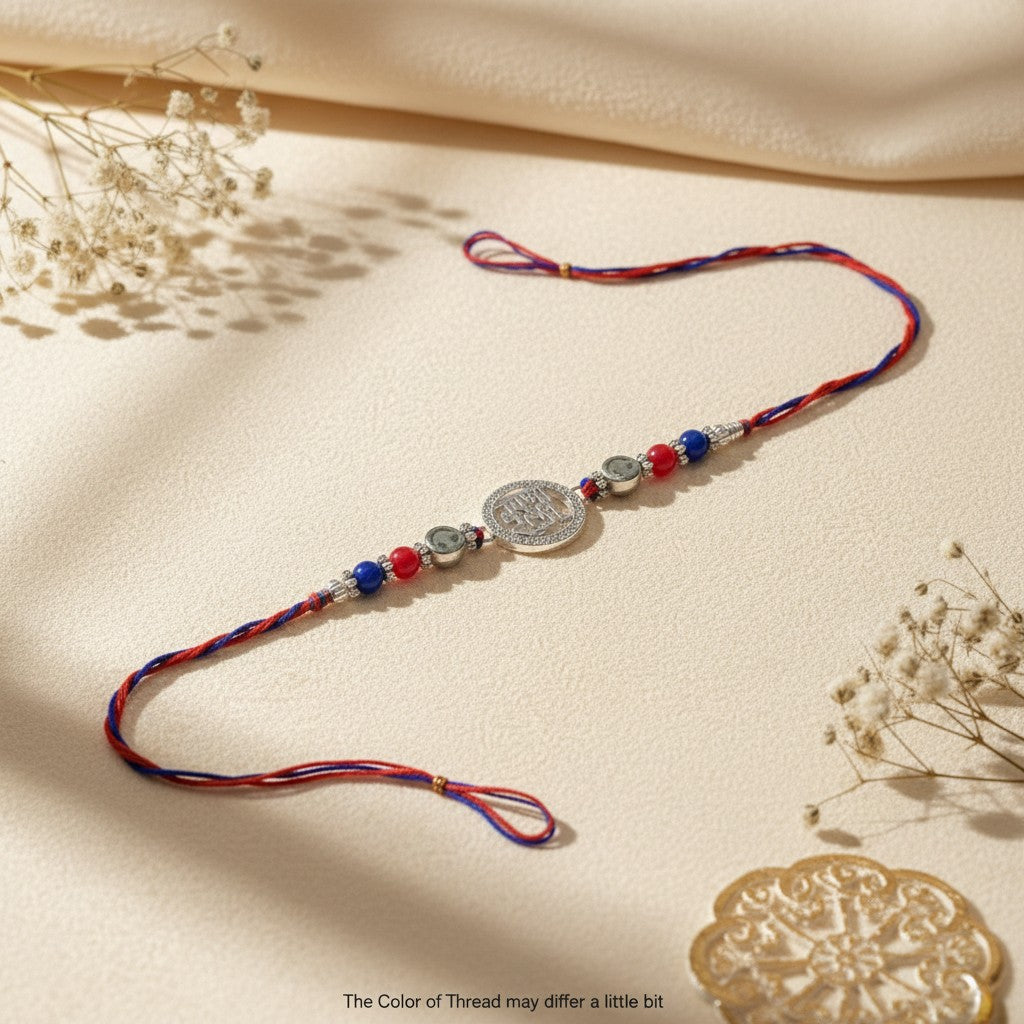 SILVAS rakhi bracelet featuring a central silver coin charm with red and blue beads on a braided thread