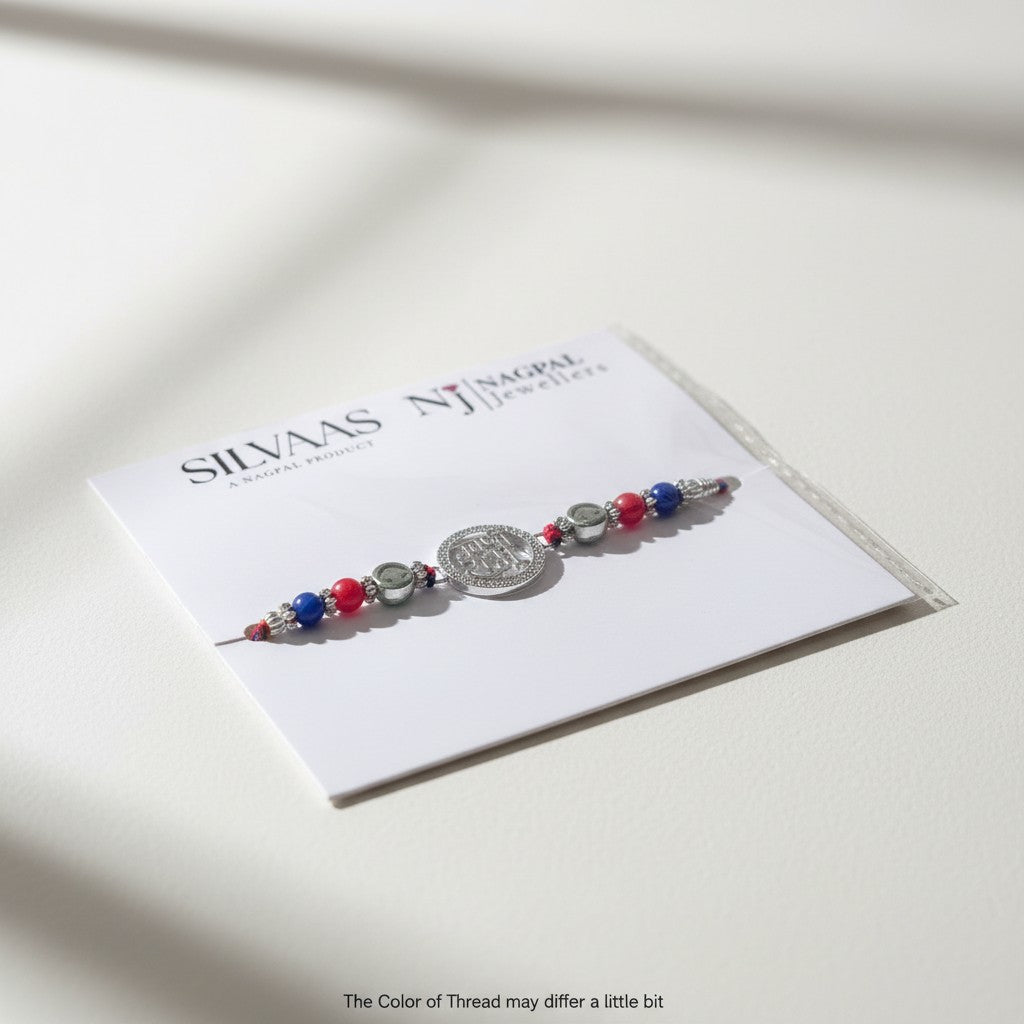 SILVAS rakhi bracelet featuring a central silver coin charm with red and blue beads on a white display card