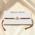 SILVAS 92.5 sterling silver rakhi featuring a deity charm on a red and yellow braided thread on a display card