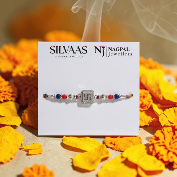SILVAS 92.5 sterling silver Swastika rakhi with red and blue beads on a vibrant thread, presented on a display card.