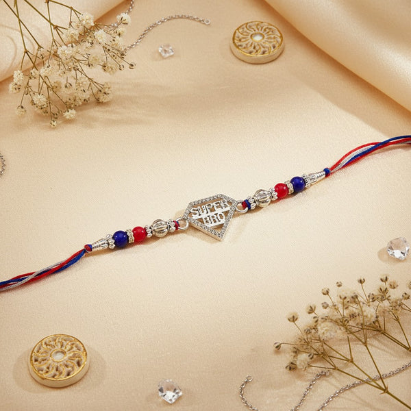 SILVAS sterling silver Super Bro rakhi with red and blue beads on a decorative thread against a silk background